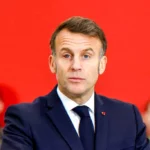 Individual in a suit against a red backdrop illustrating an article about a family photograph that went viral and sparked debate on privacy.