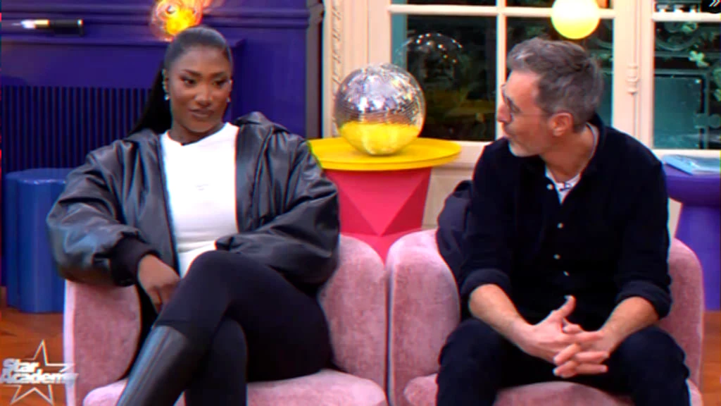 Artist and producer seated during a televised segment about the Stade de France concert