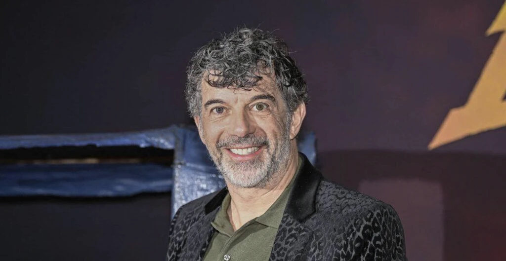 Portrait of a man in a patterned jacket at an event, illustrating an article about a television host's legal appeal and public support